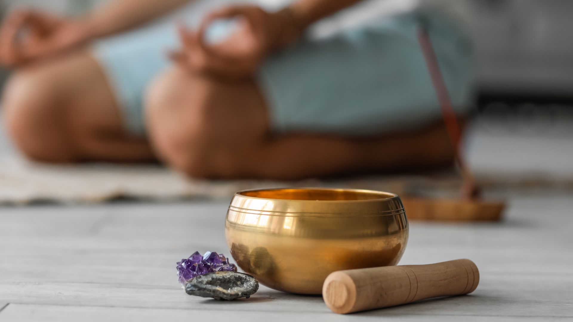 A person is practicing yoga with some crystals and a bowl.